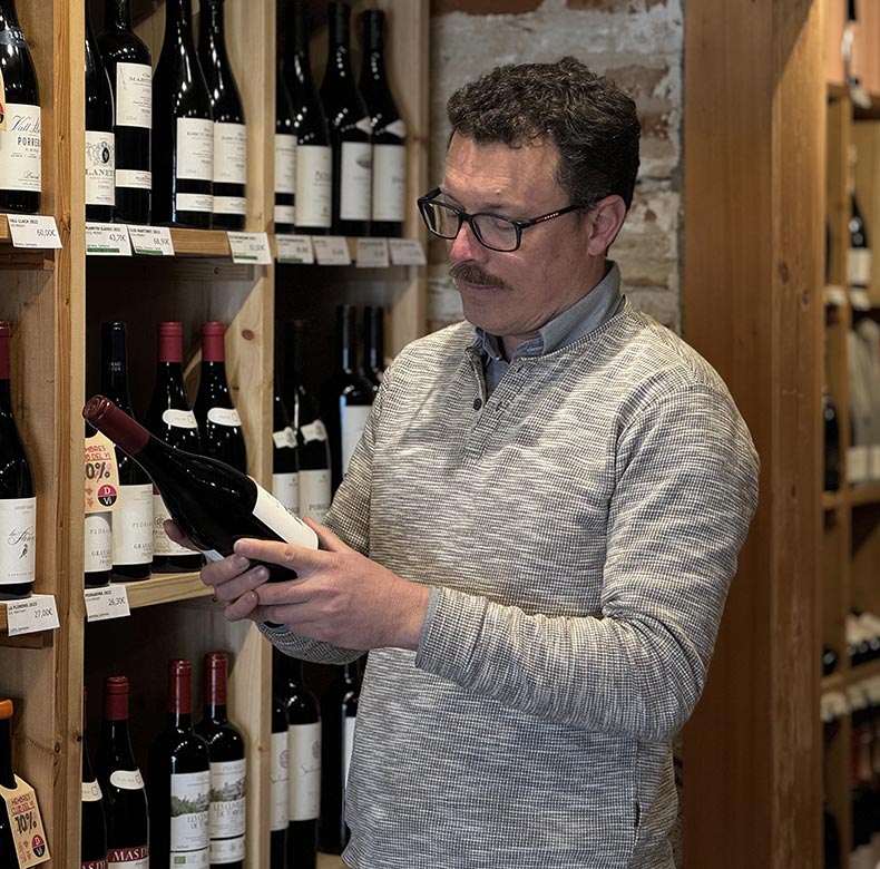 David Perramon entre estanterías de vinos en la vinoteca de Poblenou en Barcelona.