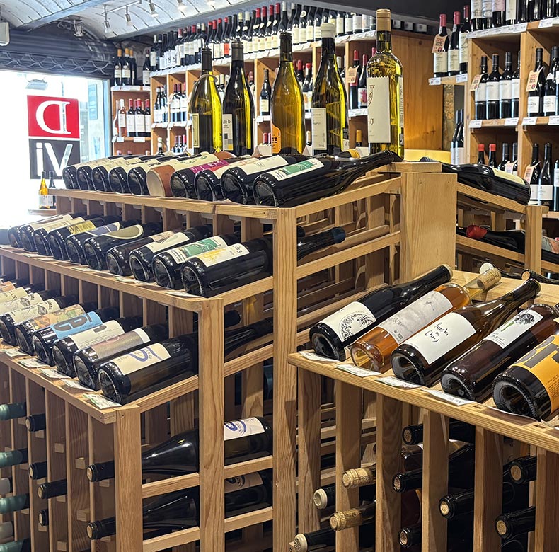 Estantes de madera con botellas de vino; espacio interior de DVI Vinoteca.